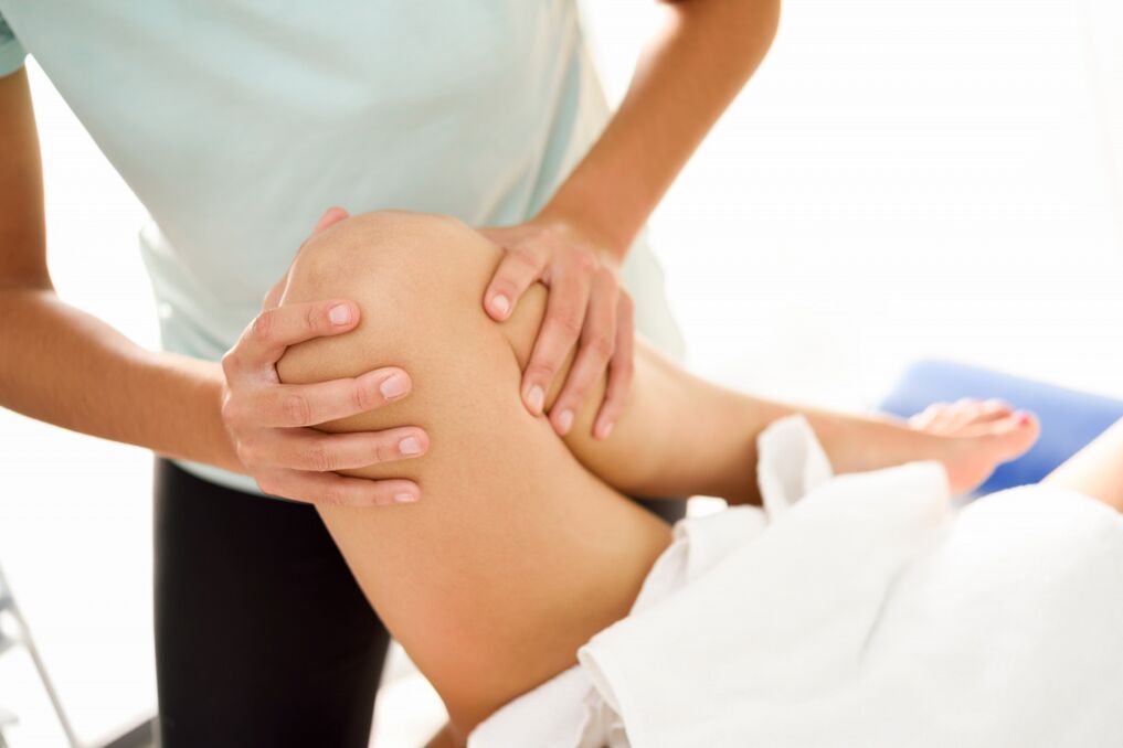 De specialist maakt de therapeutische massage met artrose van de knie